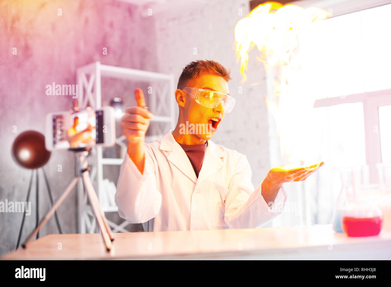 Emotional student wearing white coat making experiment with fire in
