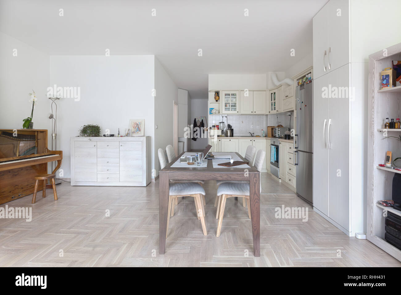 Modern bright domestic dining room interior with open kitchen and piano Stock Photo