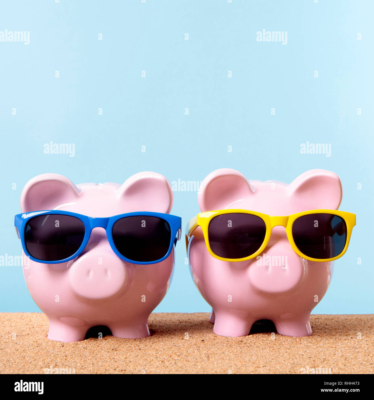 Two piggy banks beach sunglasses travel money saving Stock Photo