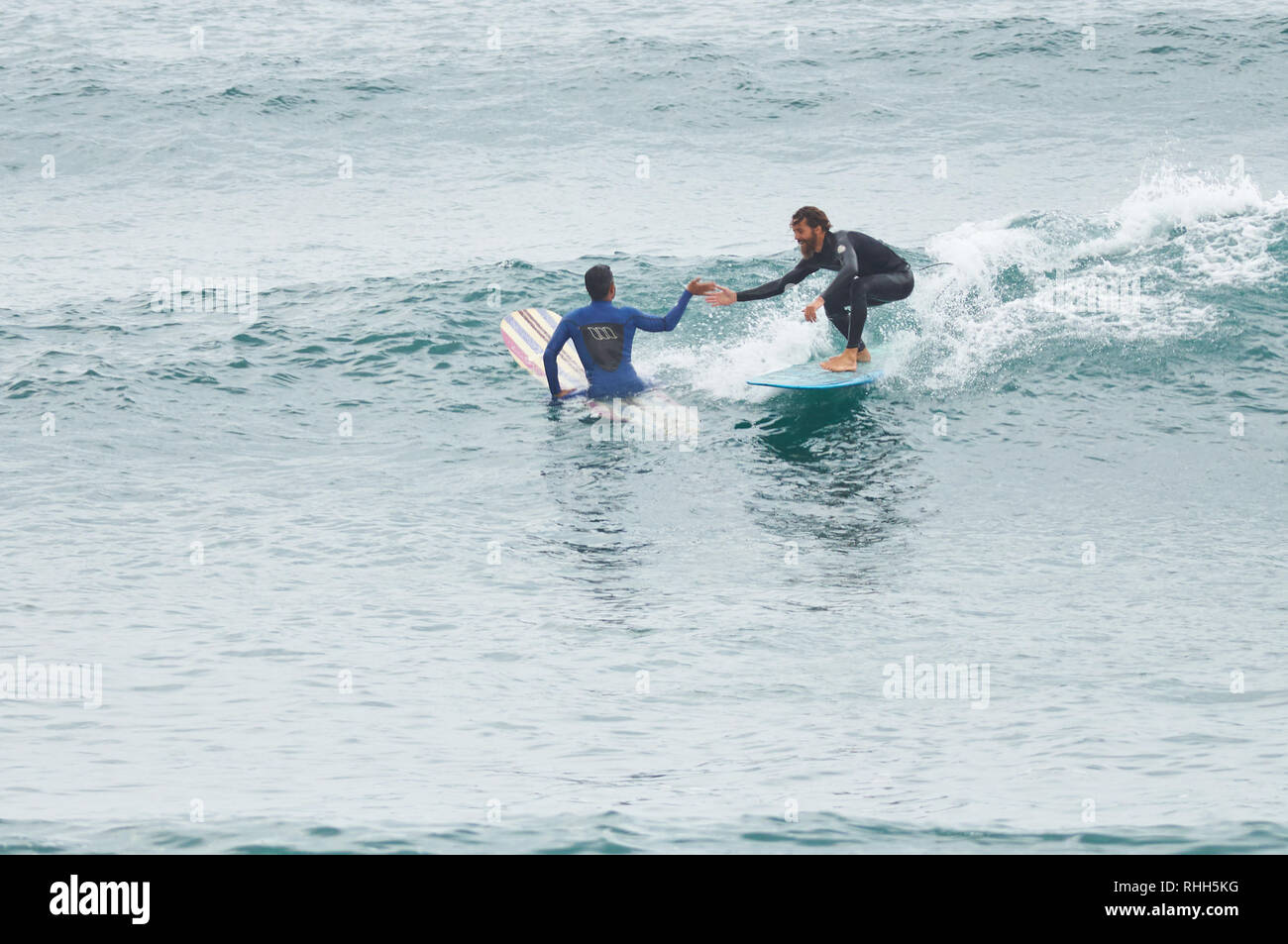 Longboard surfers giving a high five at the XIII Salinas International
