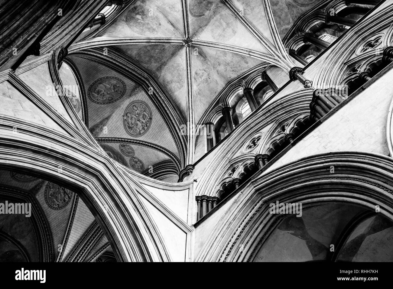 Looking up at a section of ceiling and ornate stone carved pillars and arches in Salisbury Cathedral in black and white Stock Photo