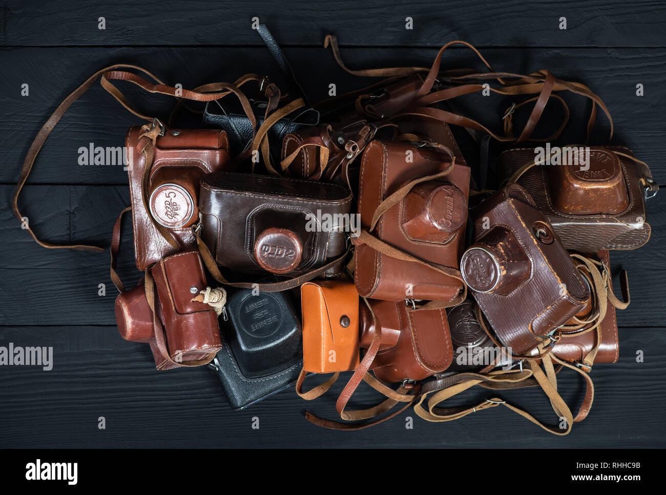 Drohobych, Ukraine - 02 February, 2019: Heap of 35mm retro cameras in leather covers on black, top view Stock Photo