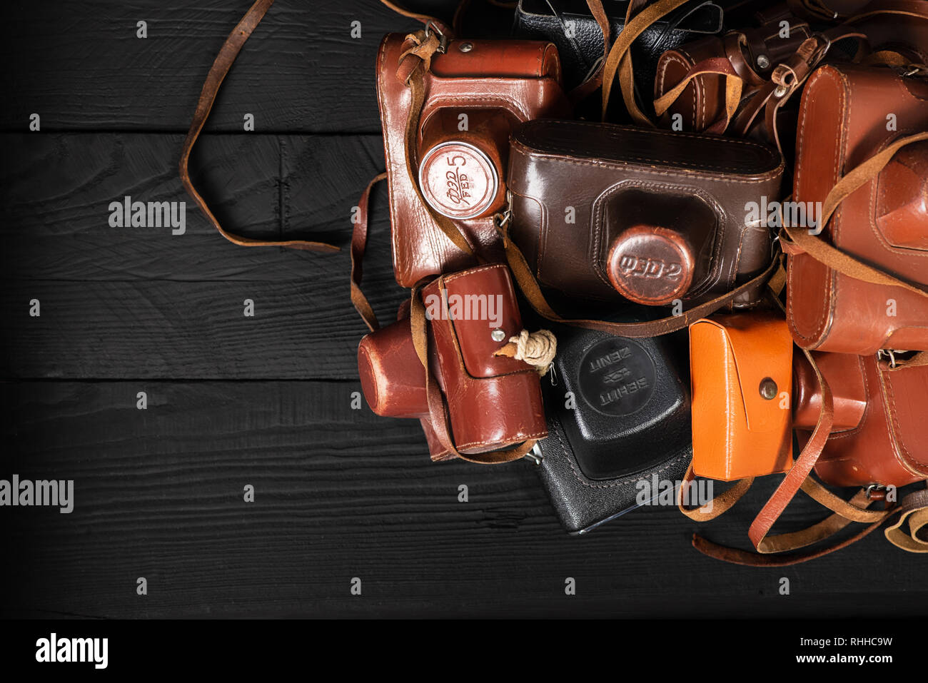 Drohobych, Ukraine - 02 February, 2019: Heap of 35mm retro cameras in leather covers on black, top view Stock Photo