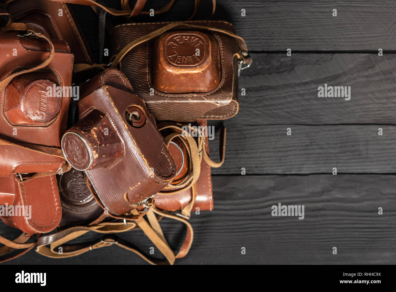 Drohobych, Ukraine - 02 February, 2019: Heap of 35mm retro cameras in leather covers on black, top view Stock Photo
