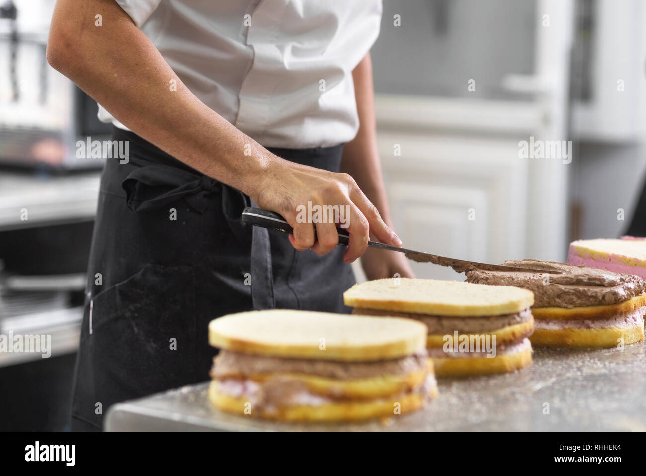 Close up of professional confectioner making a delicious cake in the pastry shop . Stock Photo