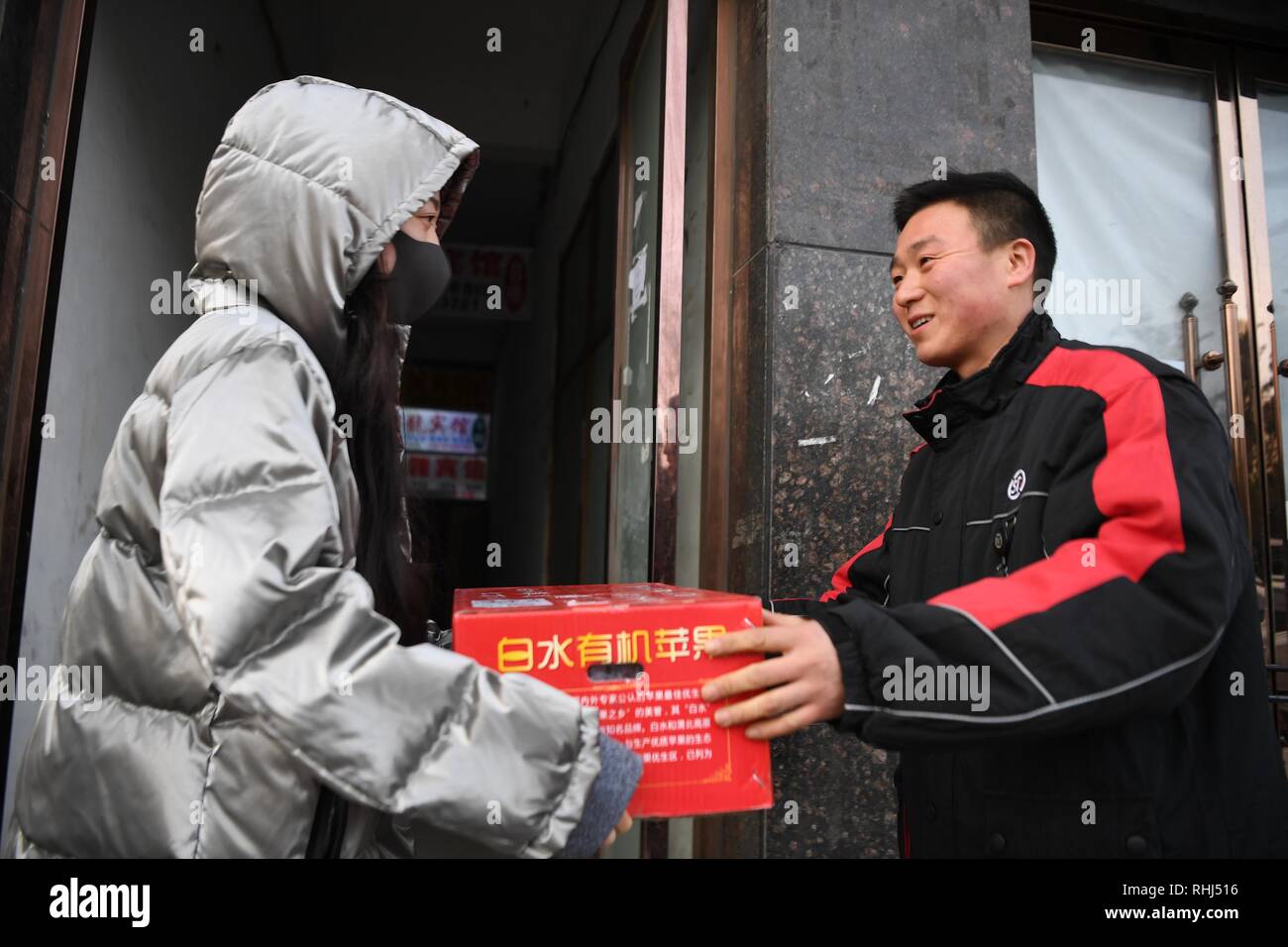 Xi'an, China's Shaanxi Province. 3rd Feb, 2019. Deliveryman Luo Feilong (R) hands a package to a customer in Xi'an, capital of northwest China's Shaanxi Province, Feb. 3, 2019. Luo Feilong, a 31-year-old deliveryman from Shaanxi Province, has been delivering packages in a community of Xi'an for four years. Luo applied for being on duty during this year's Spring Festival holiday so that other deliverymen from outside the province can return to their hometowns for family gatherings. Credit: Zhang Bowen/Xinhua/Alamy Live News Stock Photo