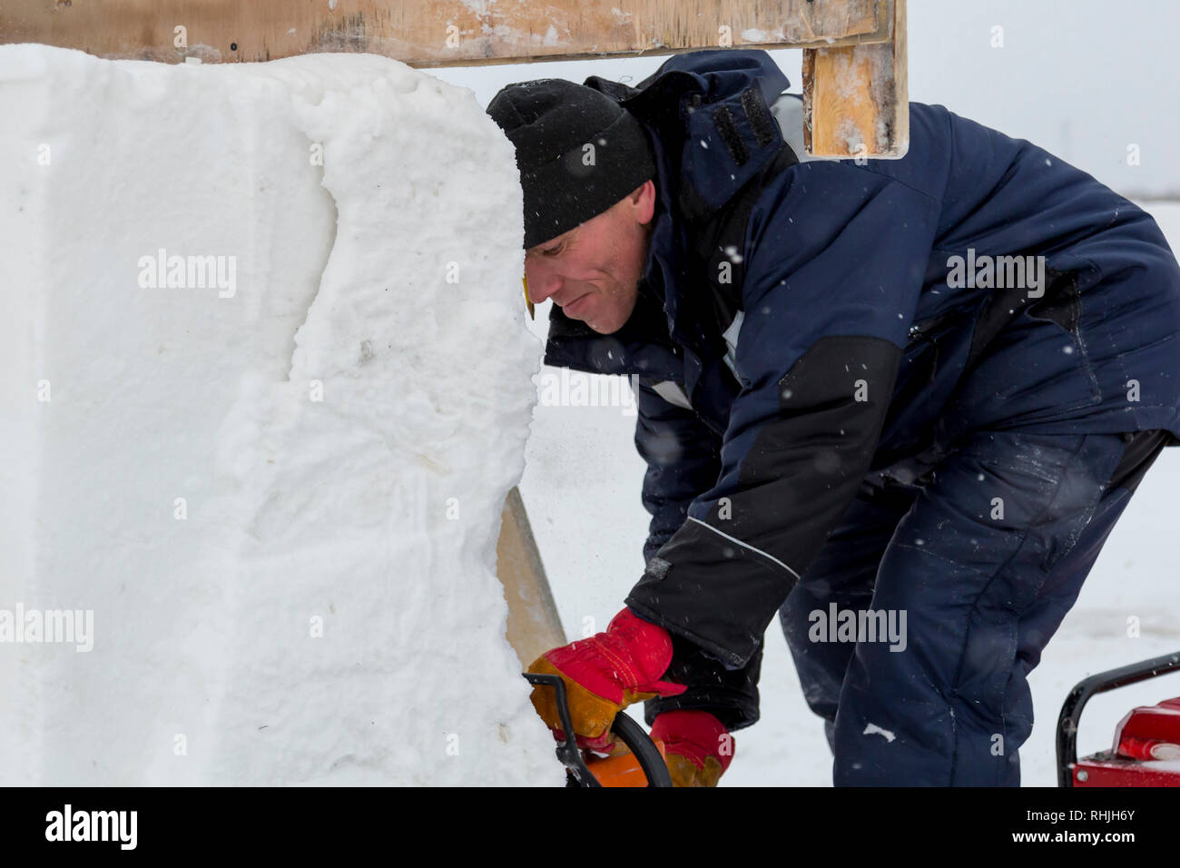 Work installer with a chainsaw in his hands undercut ice block Stock