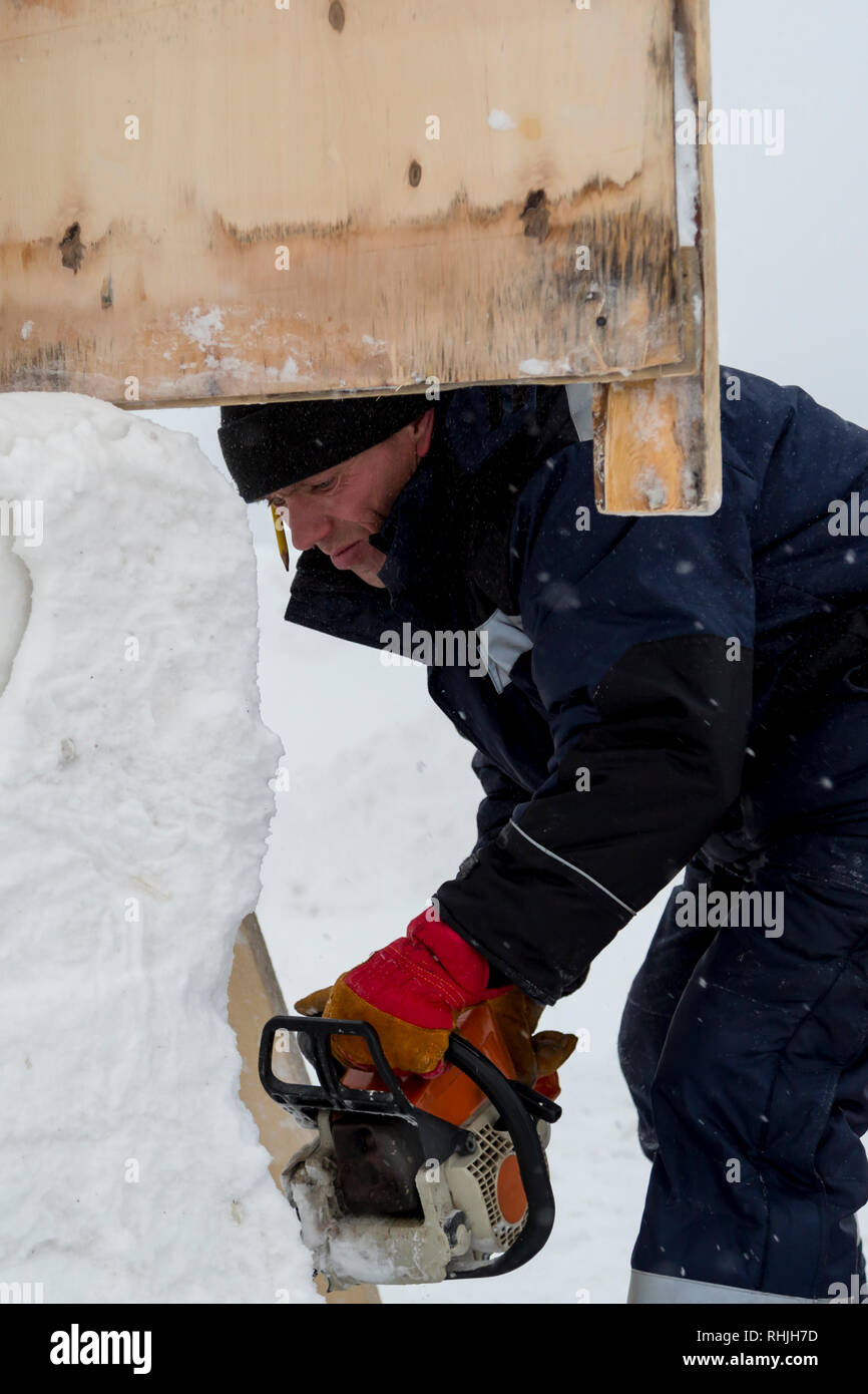 Work installer with a chainsaw in his hands undercut ice block Stock