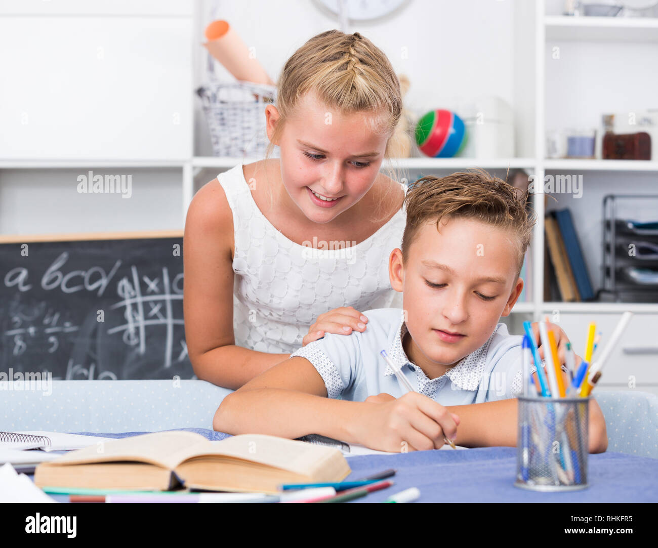 Girl is explaining to boy how to solve homework at home Stock Photo - Alamy