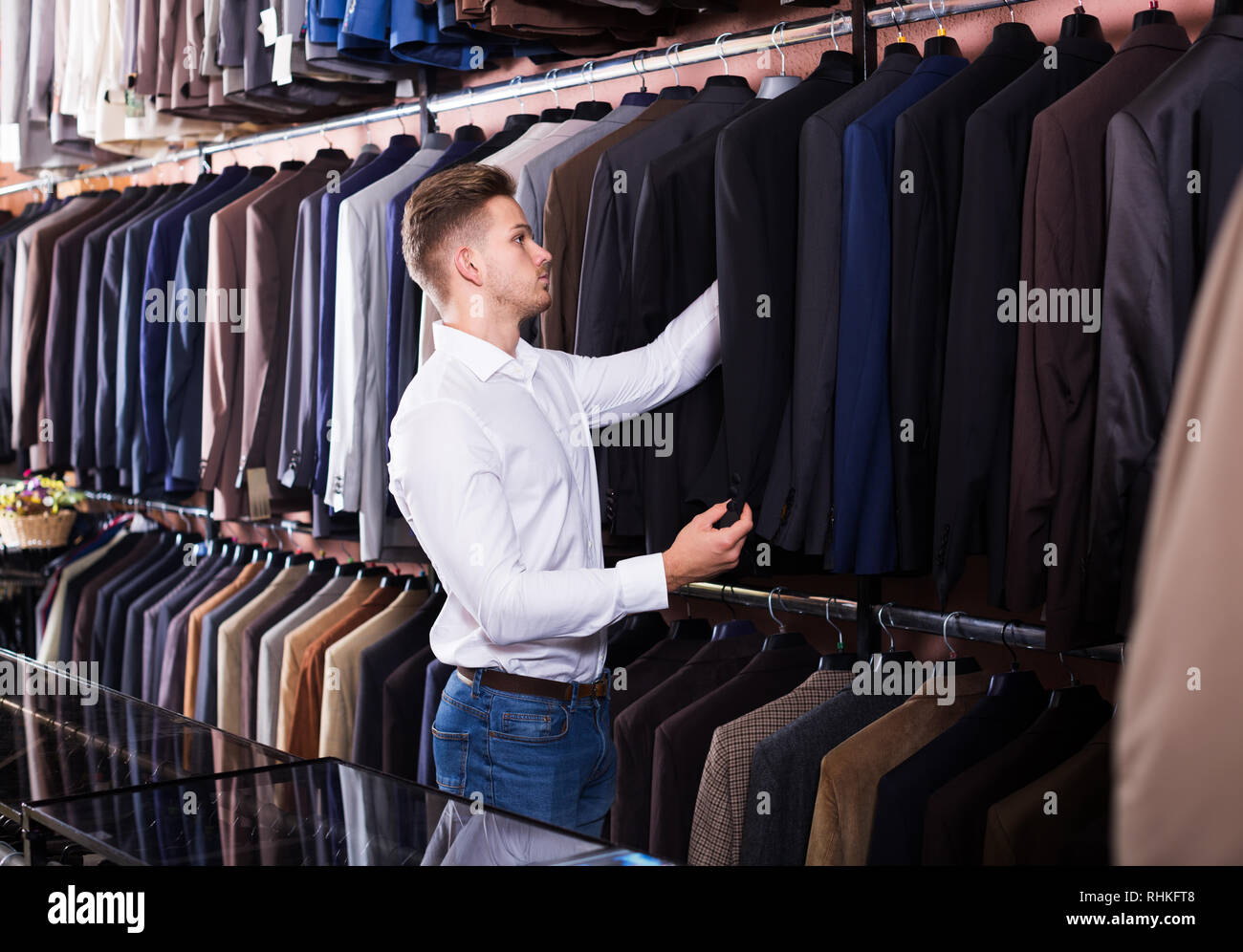 Handsome young man deciding on new suit in men’s cloths store Stock ...