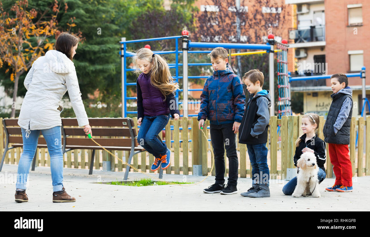 Girl jumping with skipping rope among friends at street Stock Photo - Alamy