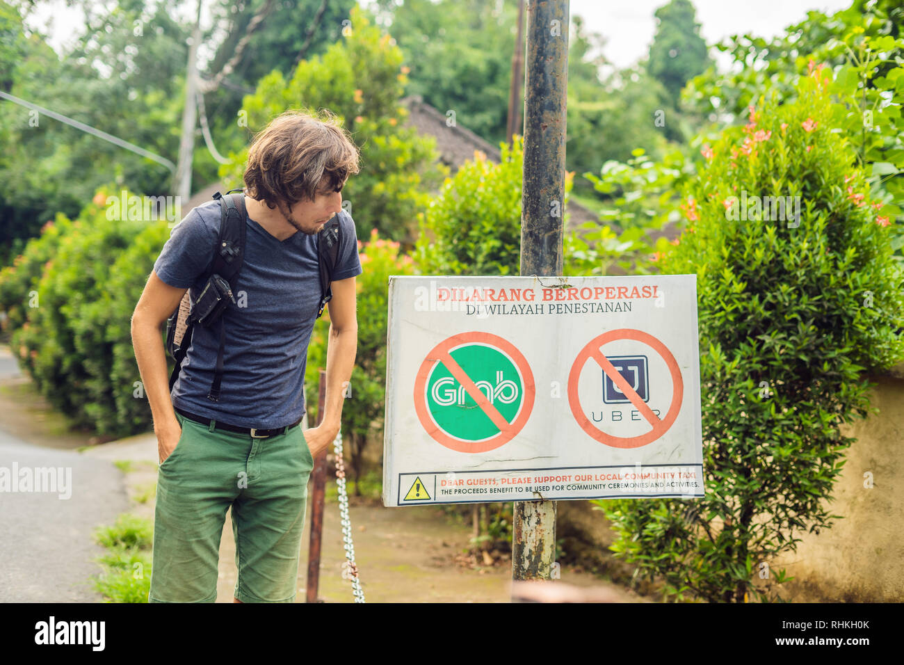 BALI, INDONESIA - 21 May, 2018: Young man looks at protest sign on a wall  in Indonesian objecting to Uber and Grab taxi drivers reads 'Uber and Grab  Stock Photo - Alamy