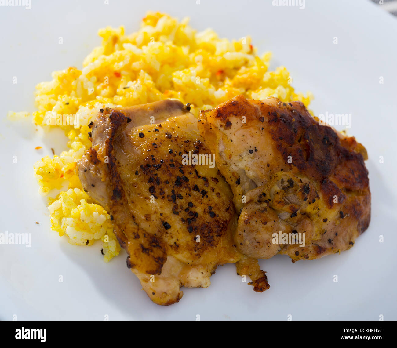 Baked chicken thighs with spicy rice served on white plate Stock Photo Alamy