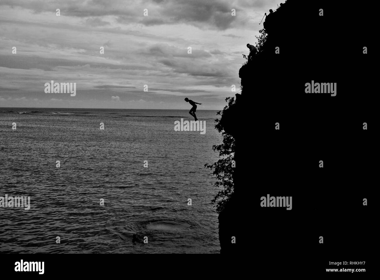 Black and white photograph of a boy jumping courageously into the sea in the south of mauritius island at macondé beach Stock Photo