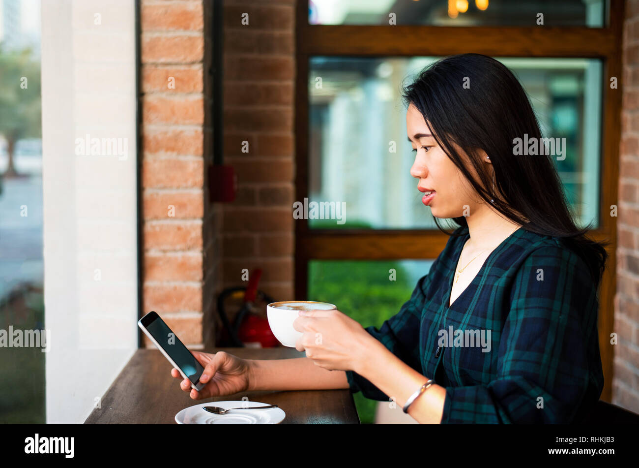 Girl having a cup of coffee and using phone in the bar Stock Photo