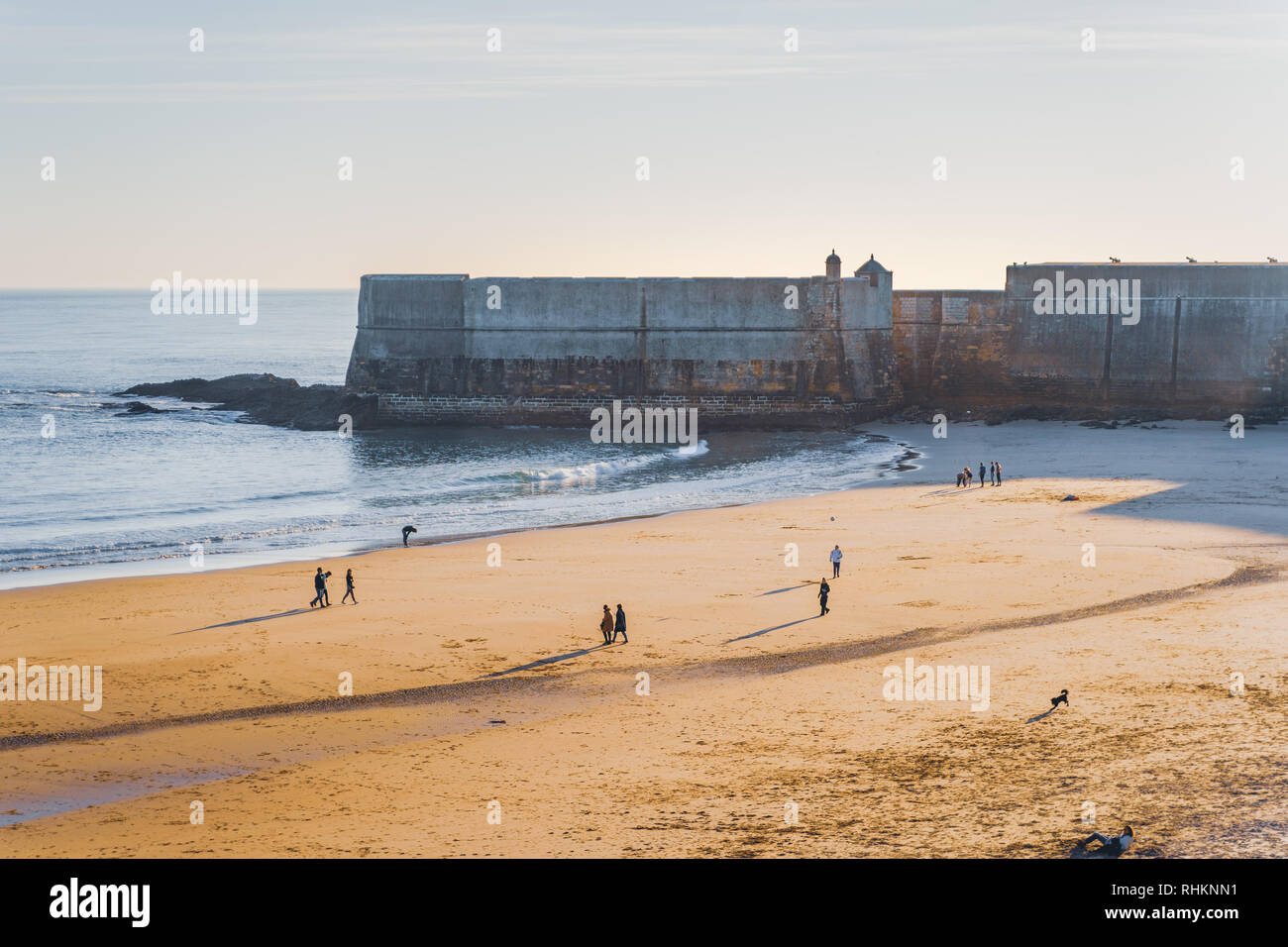 Fort in Torre beach, blue sky and ocean waves, yellow brown sand, people  walking in the sand. Low sun, fort casting shadow on the sand Stock Photo -  Alamy