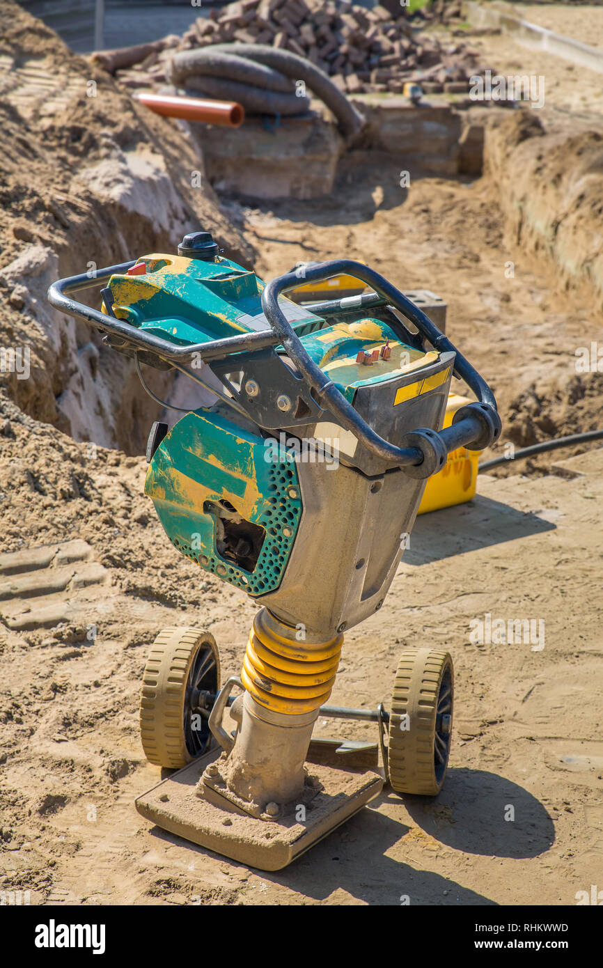 Metal vibrator as tool for road works near hole in ground Stock Photo