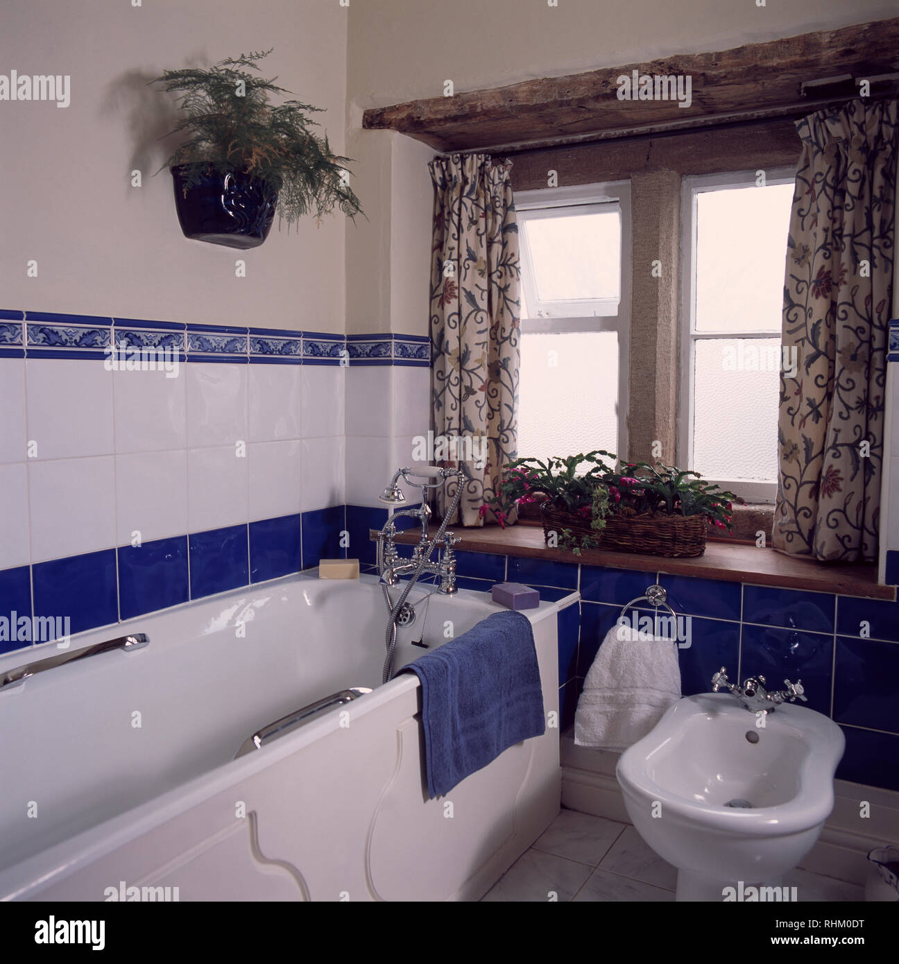 Bidet beside bath in cottage bathroom with blue and white tiling Stock Photo
