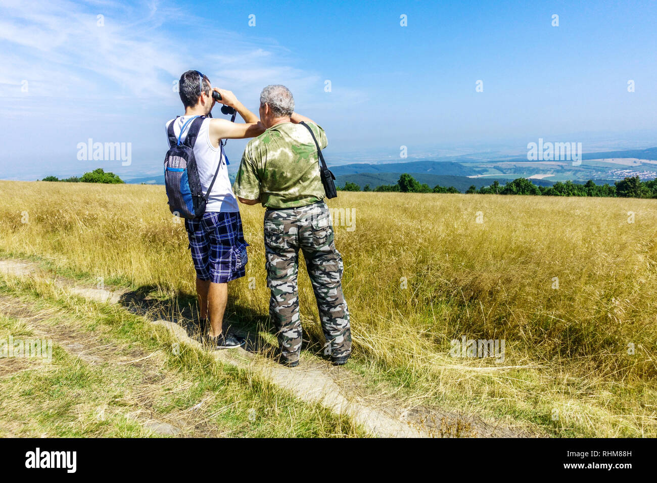 Men on a trip looking down into the valley, mountain meadow in the White Carpathians Mountains, Velka Javorina, Czech Slovak border Stock Photo