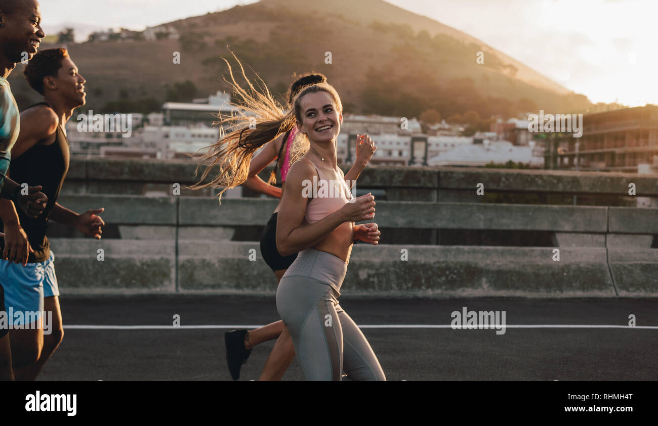 Fit young woman running with friends in the city. Runners training outdoors in morning. Stock Photo