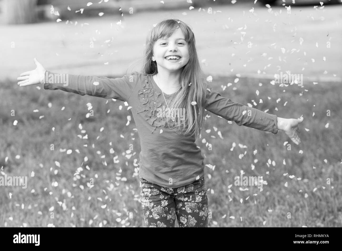 Little Girl On Green Grass Play With Flower Petals In Spring