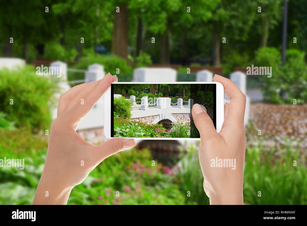 A man is making a photo of bridge over river in the Bernardine Garden in Vilnius on a mobile phone Stock Photo