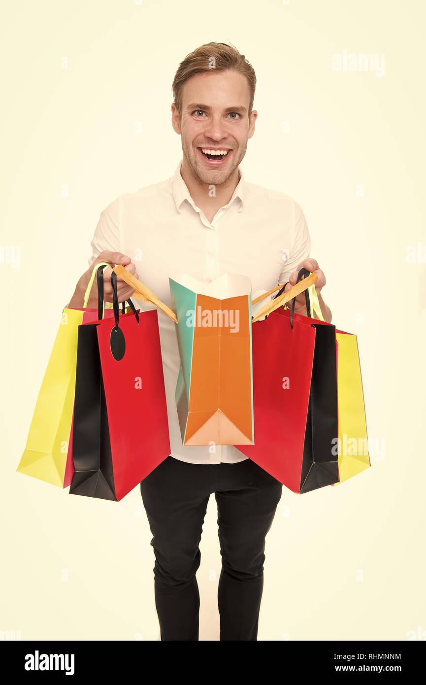 Man happy client received packages purchases. Delivery service. Guy buy fashionable clothes online. Online shopping concept. Man takes advantages online shopping. Guy carries bunch colorful bags. Stock Photo