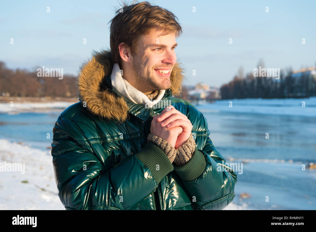 Winter stylish menswear. Winter outfit. Hipster winter fashion outfit. Guy wear jacket with hood on frosty winter day. Man bearded stand warm jacket snowy nature background. Wind resistant clothes Sto...