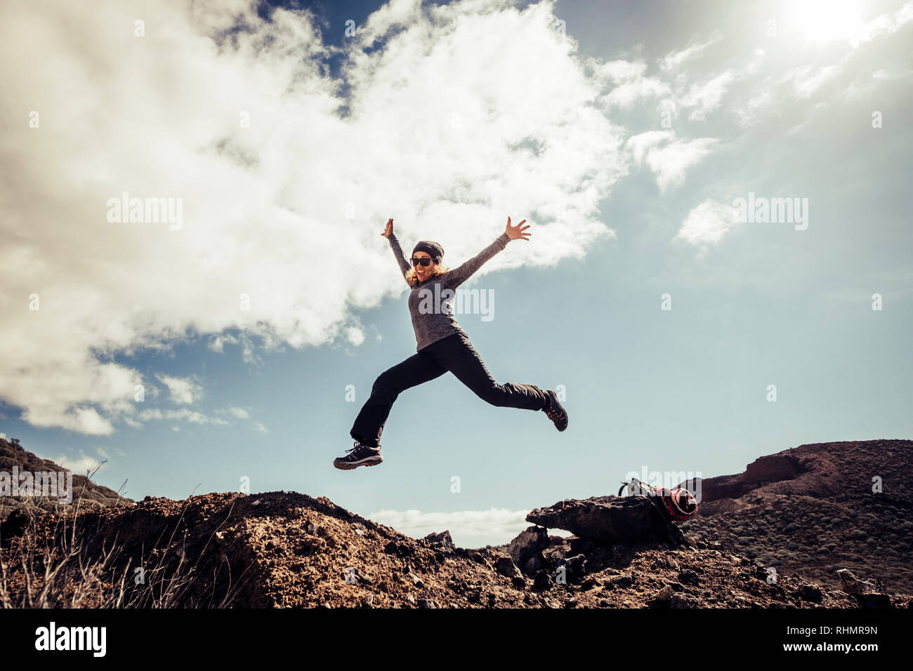 Young middle age woman jump to the stones for happiness and success concept during a travel touristic trekking - freedom and carzy modern people conce Stock Photo