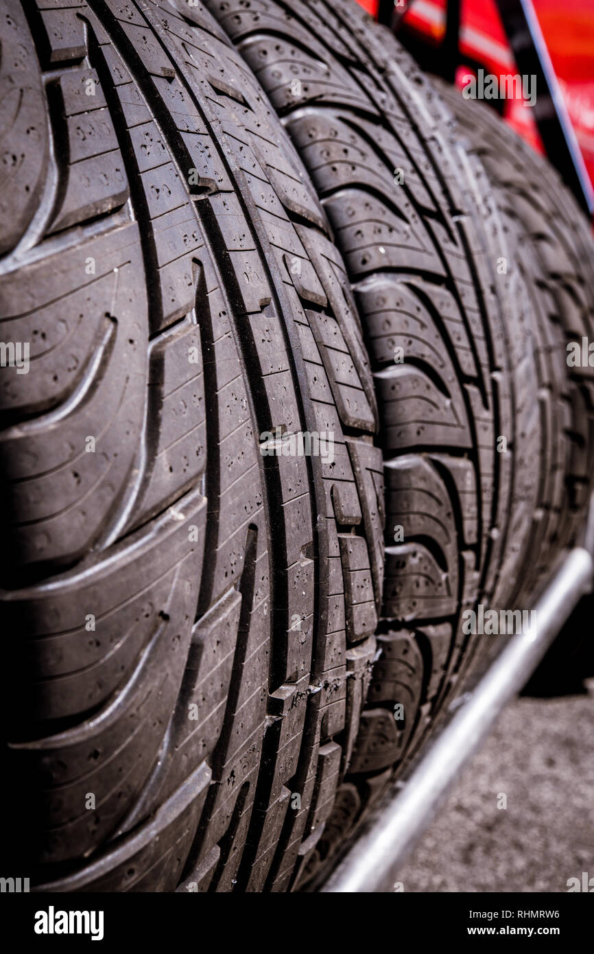 Detail of racing car tire set with wet tread aligned on a shelf, selective focus Stock Photo