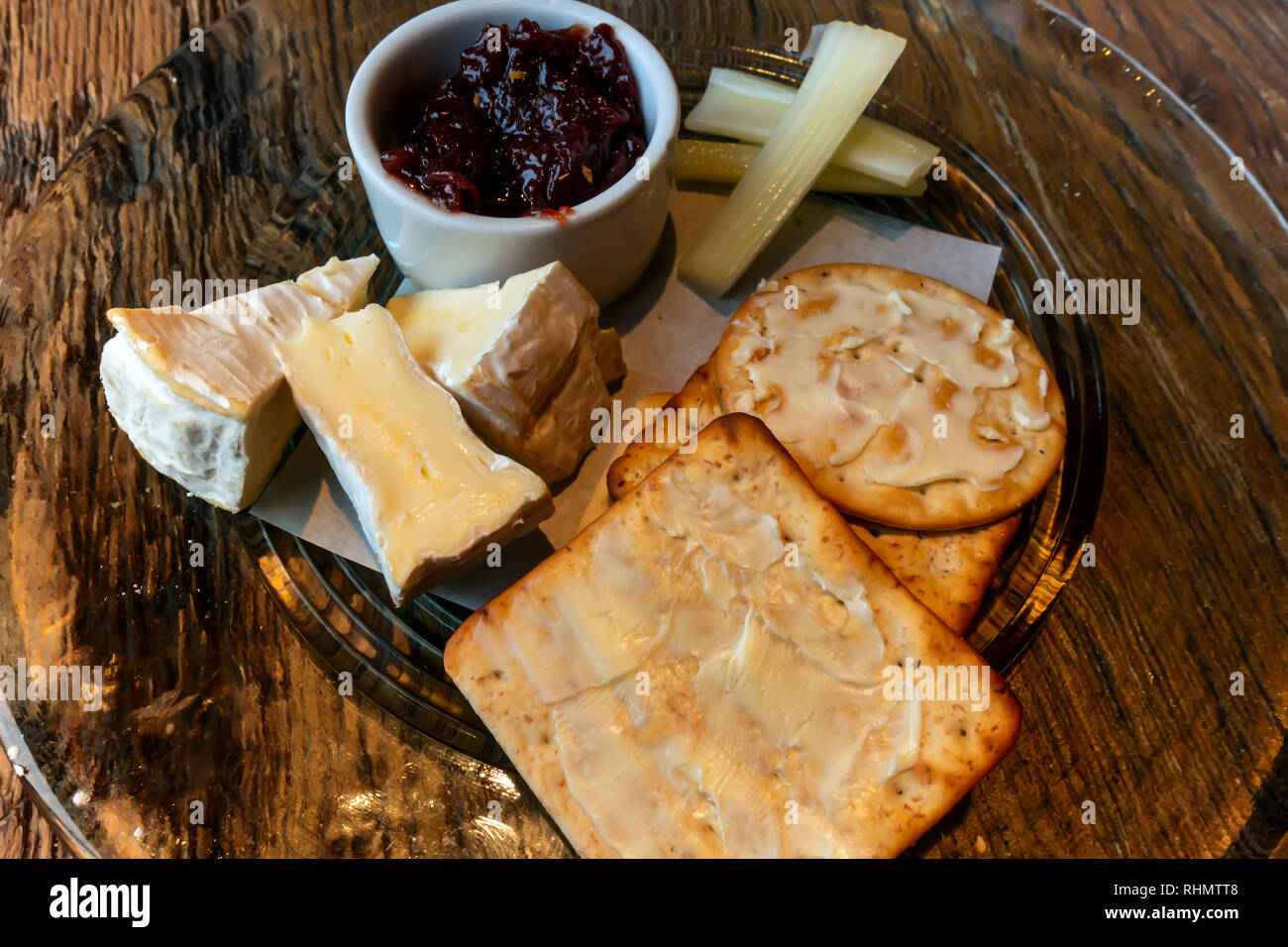 Camembert Cheese buttered biscuits celery and pickle served on a glass plate Stock Photo