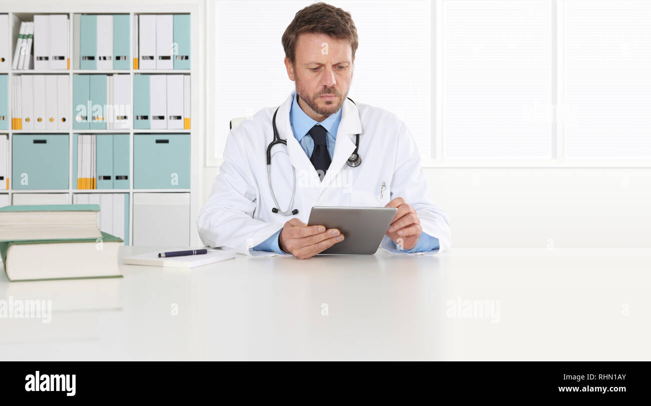 Doctor Writing Prescription At Desk In Medical Office With Digital