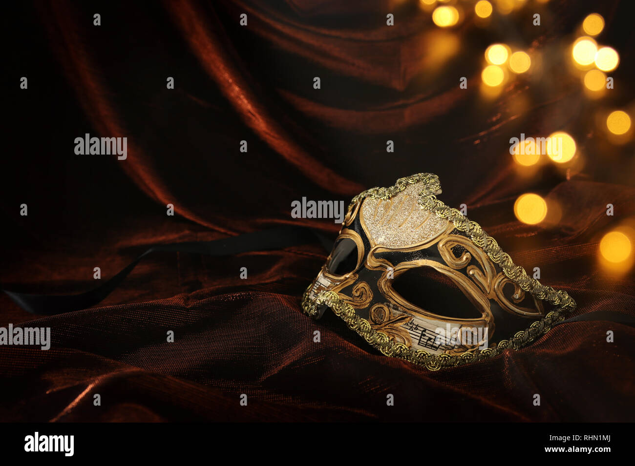 Photo of elegant and delicate gold venetian mask over dark velvet and