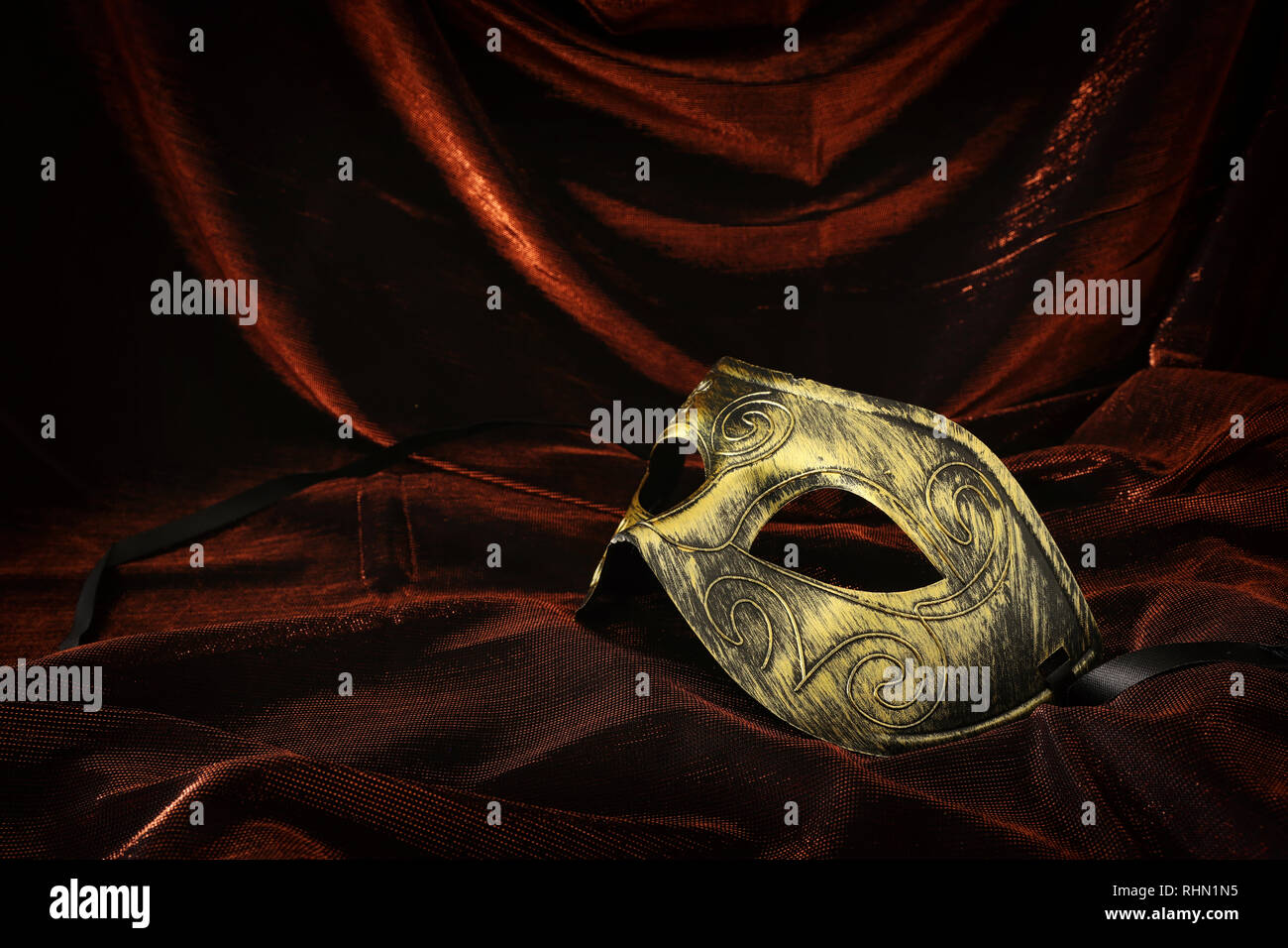 Photo of elegant and delicate gold venetian mask over dark velvet and