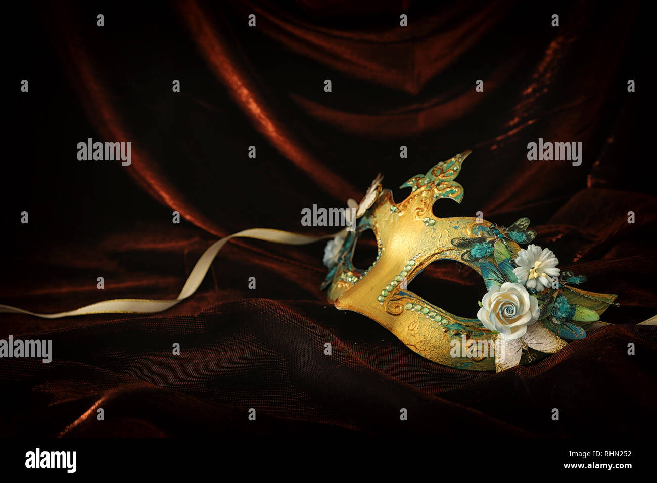 Photo of elegant and delicate gold venetian mask over dark velvet and