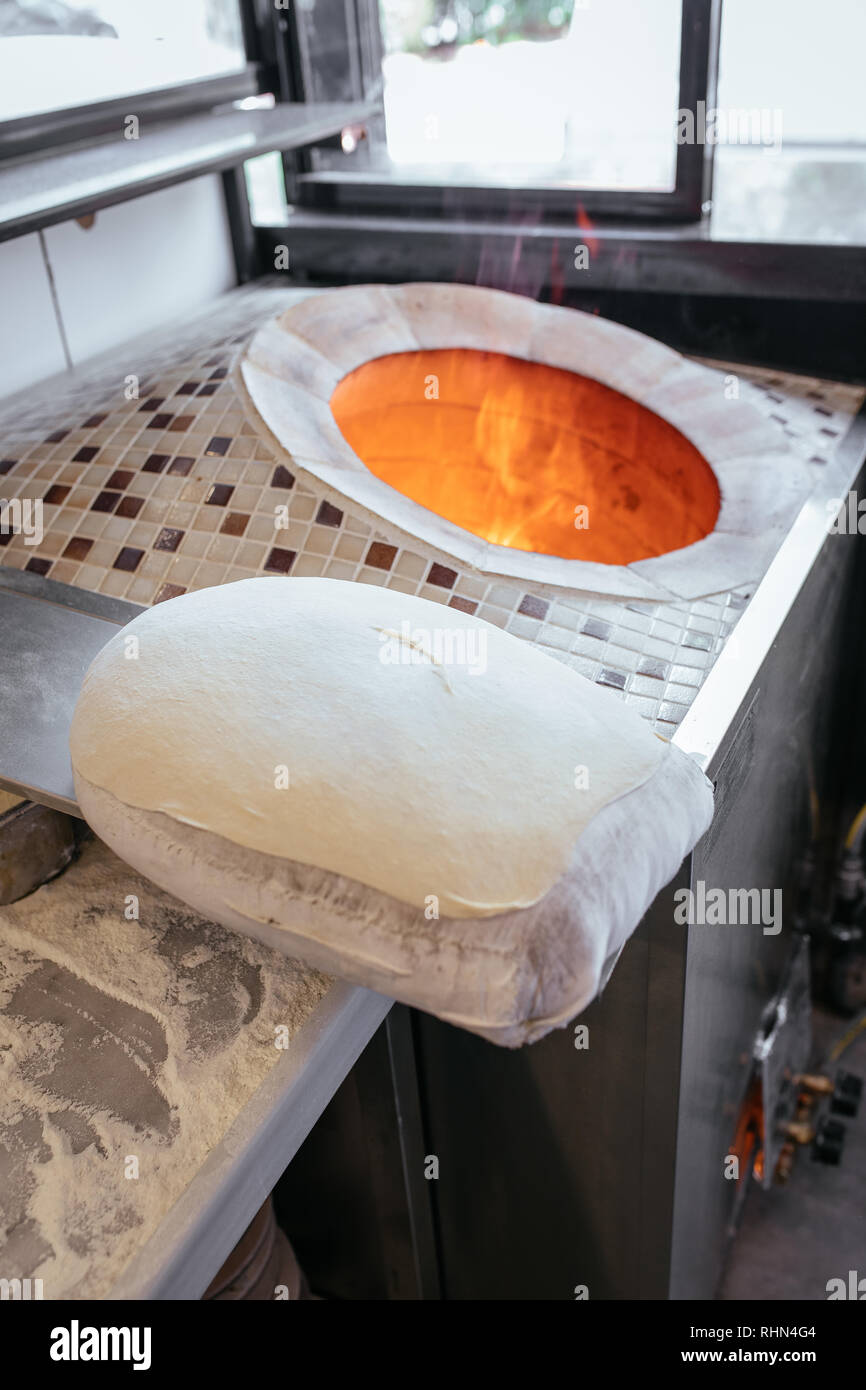 Traditional turkish wood fired stone brick oven and pita or pide bread dough. This stone oven for Turkish pide or pita bread. Also known as Tandir. Stock Photo