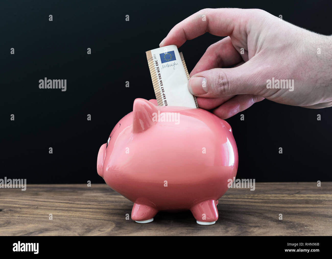 hand putting money in piggy bank  Stock Photo
