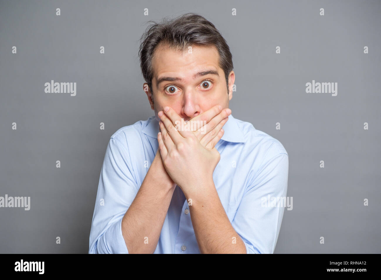 Man covering mouth on gray background Stock Photo