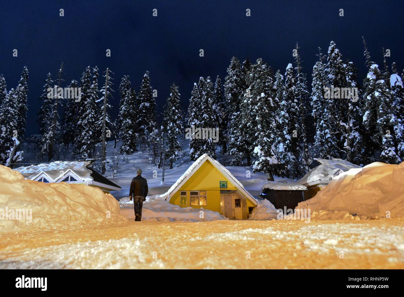 A man seen walking through a snow covered road during night at a famous ski resort in Gulmarg, about 55kms from Srinagar, Indian administered Kashmir. Gulmarg, situated in the foothills of the Himalayas at 2,745 meters (9,000 feet) above sea level, is regarded as one of the leading ski destinations in South Asia. Stock Photo
