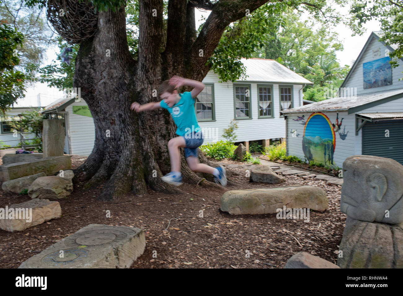 Boy jumping on sandstone blocks in Nimbin, New South Wales, Australia Stock Photo