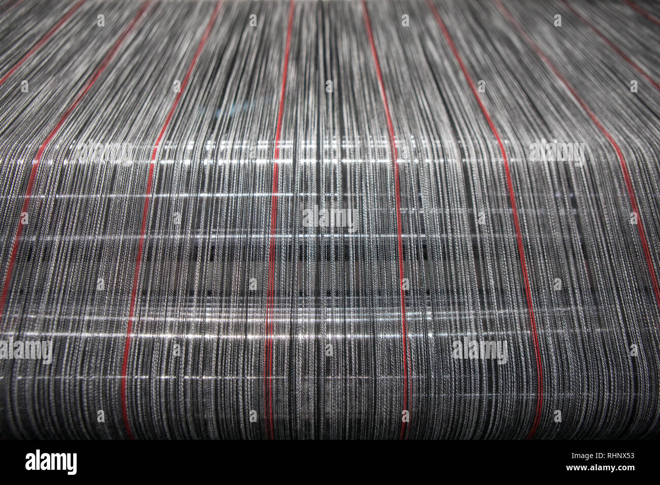 Yarn thread lines on the weaving loom machine. A loom machine for clothing or woven label in textile factory. Weaving machine for garment industry. Stock Photo