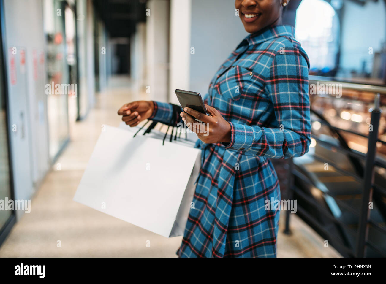 Black female person with phone and shopping bags in mall. Shopaholic in  clothing store, consumerism lifestyle, fashion Stock Photo - Alamy