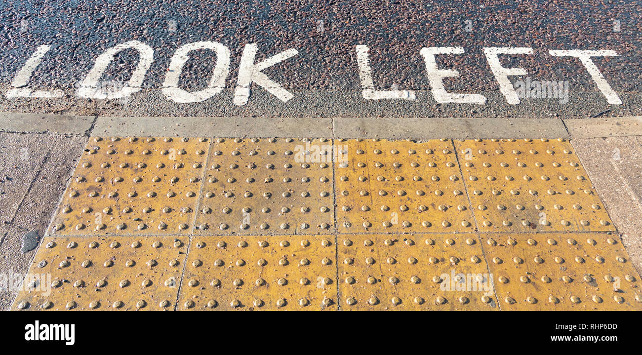 Look Left written in white capital letters at a pavement edge complete with tactile paving for the visually impaired or blind Wallasey Village Februar Stock Photo