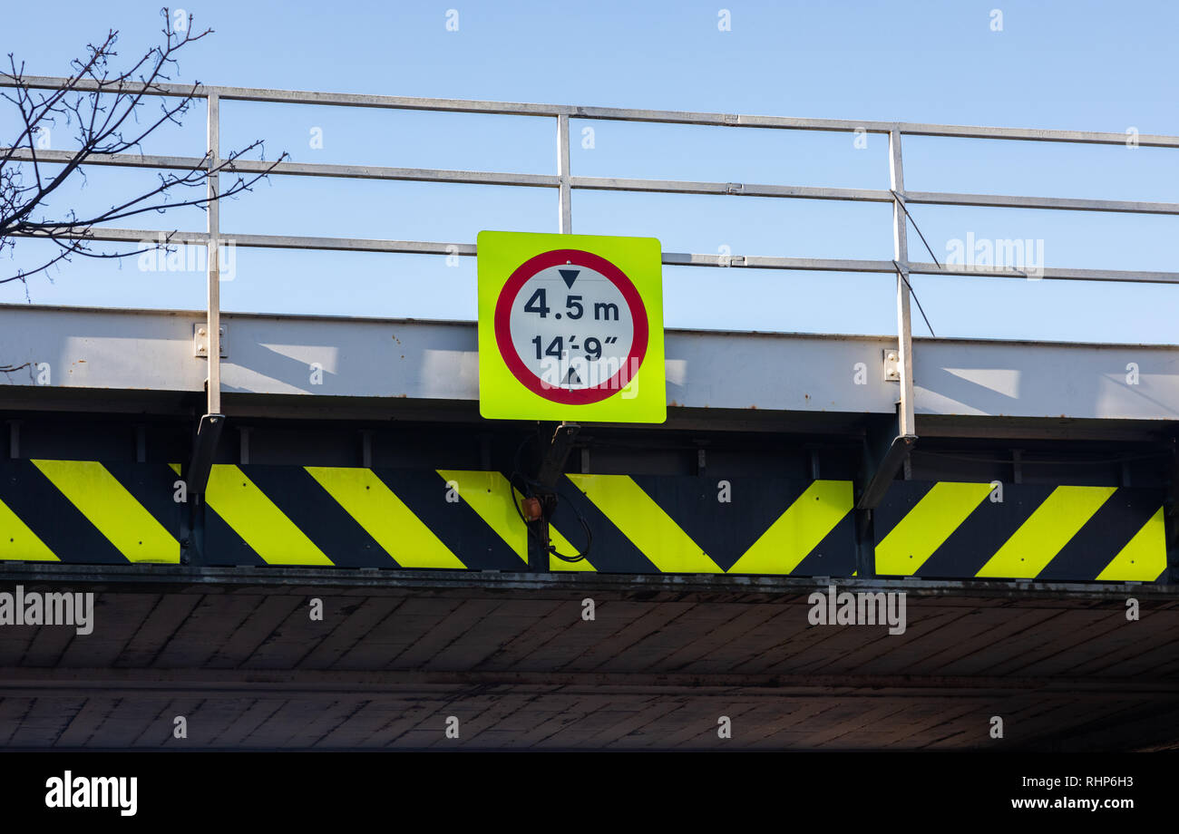 Fluorescent warning sign with red circular border and black and yellow markings indicating a low railway bridge with height limit Wallasey Village Feb Stock Photo