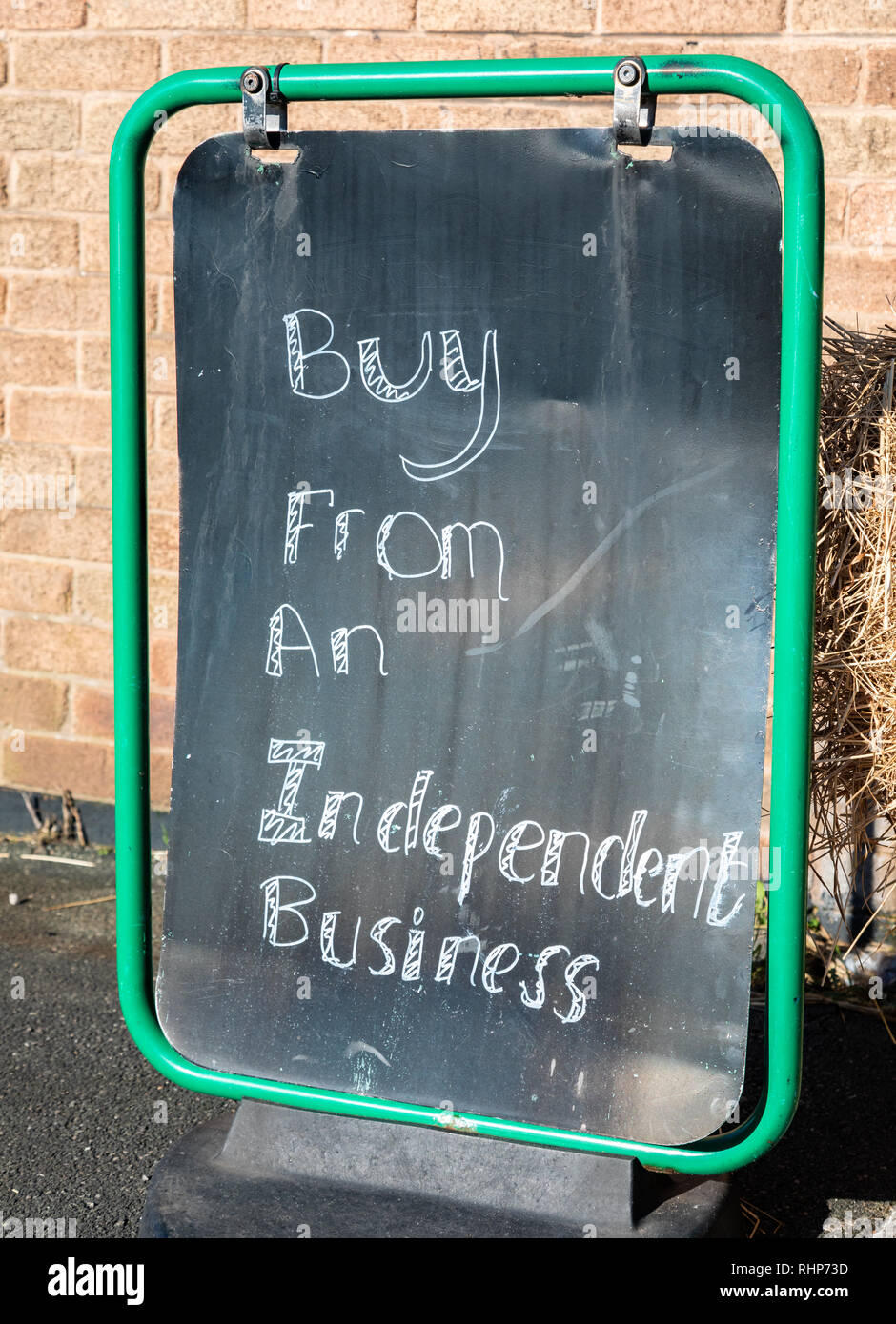 close up of a metal sign with a black background and white lettering outside a local shop encouraging people to buy from an independent business Walla Stock Photo