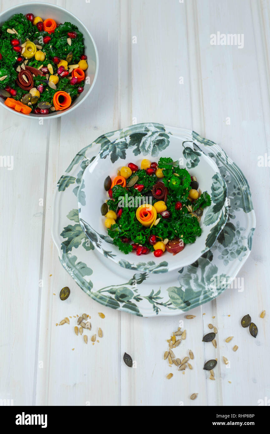bowl with kalettes (a cross between Brussels sprouts and green cabbage), chickpeas, colourful carrots, pomegranate seeds and various seeds Stock Photo
