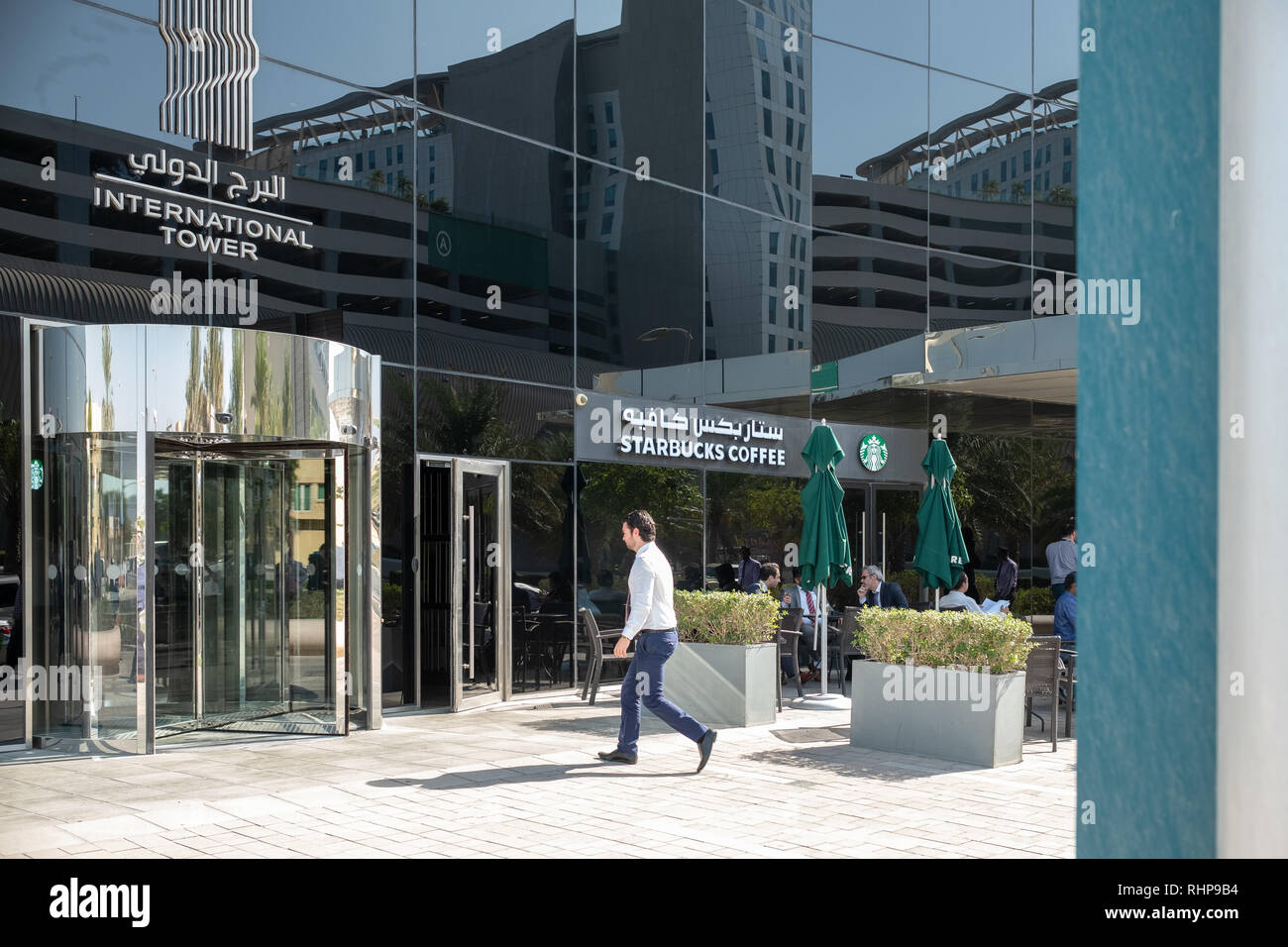 People sitting outside Starbucks Coffee in a shade at International