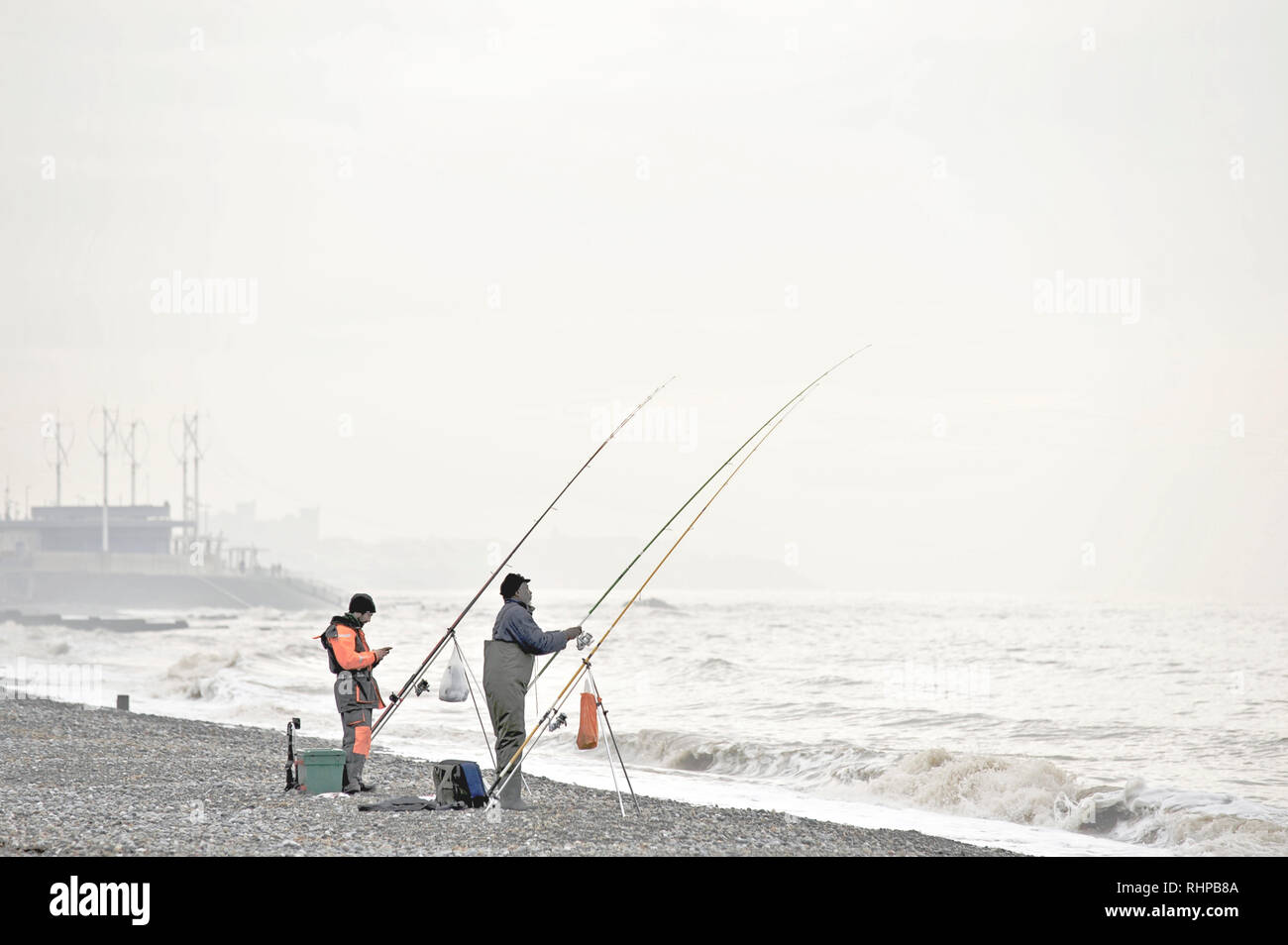 Two sea anglers fishing for cod on a January day with a rough sea off Rossall beach Stock Photo