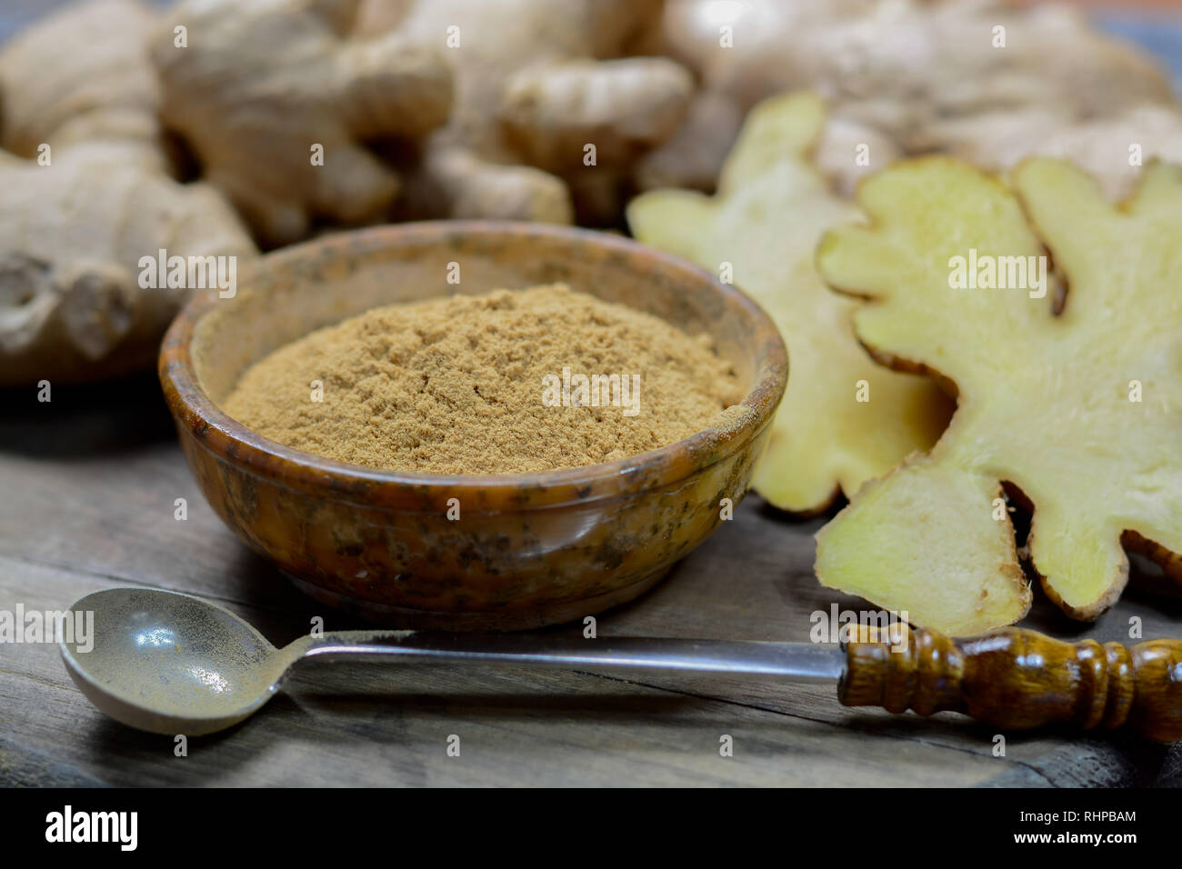 Fresh raw ginger roots from China and bowl with ginger powder close up ...