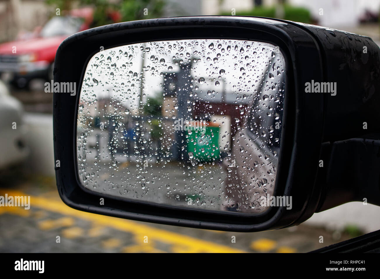 Water droplets on a car mirror, reflection on glass with raindrops Stock Photo